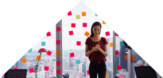 Mixed race secretary working in modern office in skyscraper, writing and sticking adhesive notes with tasks on window  
